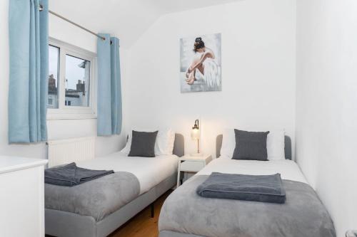 a bedroom with two beds and a window at Cheltenham-Cosy 2 Bedroom House-WiFi-Garden-Pets in Cheltenham