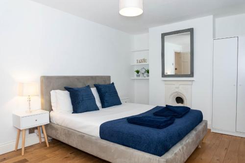 a white bedroom with a large bed with a blue blanket at 2 Bed House-Great location in Cheltenham-Free WiFi in Cheltenham