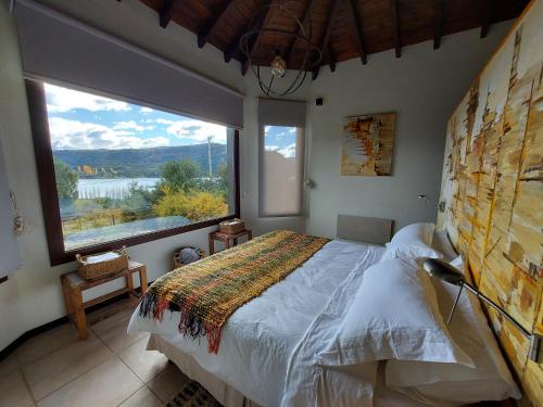 1 dormitorio con cama y ventana grande en Lares de Yaima en Cholila