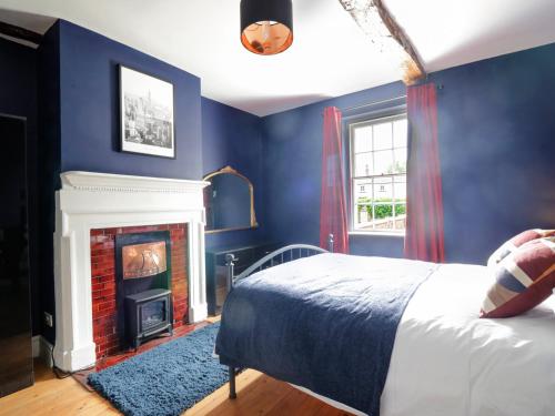 a blue bedroom with a bed and a fireplace at The Hollies in Carlisle