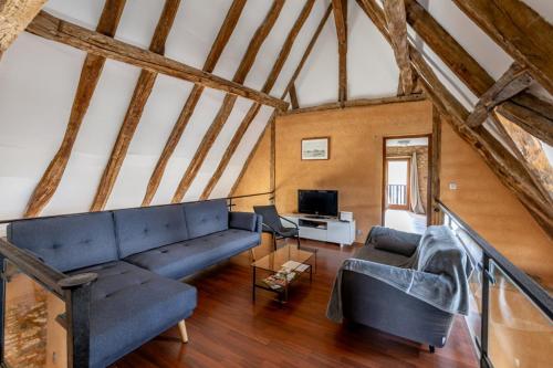 a living room with a blue couch and a tv at Gîte lOragée Les Farguettes in Cadouin