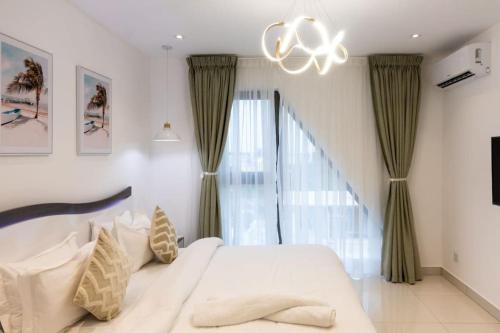 - une chambre avec un lit blanc et un lustre dans l'établissement Skyline 2 Bed Loft @ The Lennox, à Accra