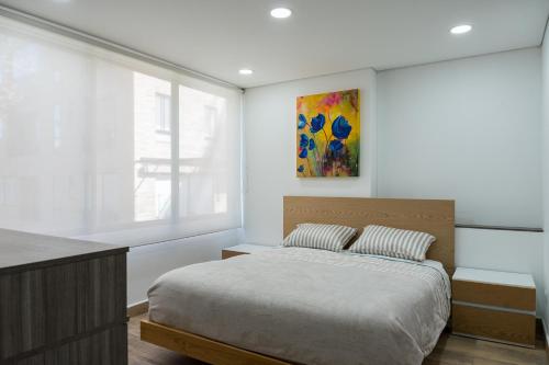 a bedroom with a bed and a painting on the wall at FASCINANTE ALOJAMIENTO in Bogotá