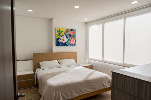 a bedroom with a bed and a painting on the wall at FASCINANTE ALOJAMIENTO in Bogotá