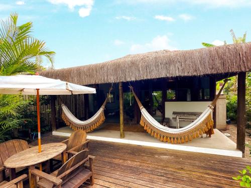 カライーバにあるCasa maravilhosa beira mar na vila de Caraívaのハンモックとテーブルと椅子のあるリゾート