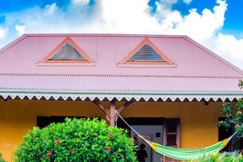 a pink house with a pink roof at Mora Mora, villa créole avec piscine & jardin in Le Vauclin