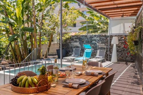 a table and chairs on a patio with a pool at Villa Quebra Costas by An Island Apart in Funchal
