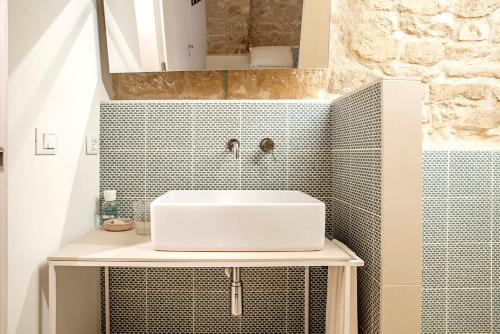 a bathroom with a sink and a tiled wall at Mazzini 5 in Ragusa