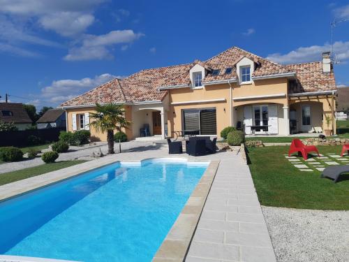 a villa with a swimming pool in front of a house at Villa du Courboulay in Sargé Les Le Mans 