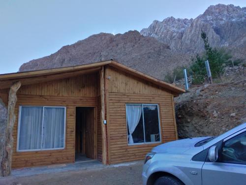 a wooden cabin with a car parked in front of it at Hermosa cabaña para 4 personas con tinaja-Cochiguaz Valle de Elqui in Monte Grande