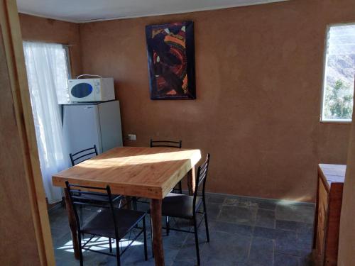 a dining room table with chairs and a refrigerator at Hermosa cabaña para 4 personas con tinaja-Cochiguaz Valle de Elqui in Monte Grande