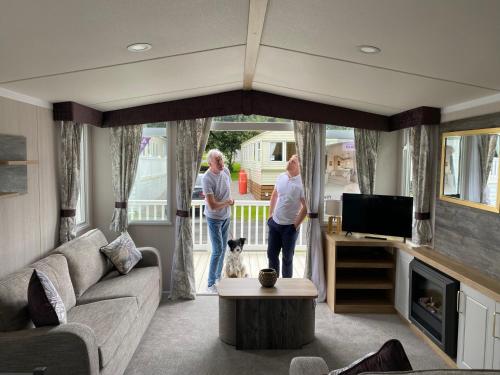 two people standing in a living room with a dog at Splendid View Caravan in Gisburn