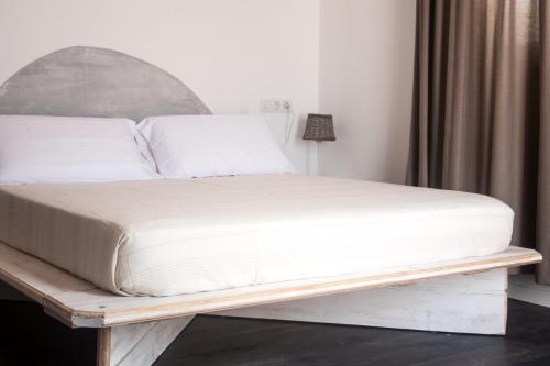 a bed with a white mattress on a wooden platform at Hostal Bon Sol in Sant Ferran de Ses Roques