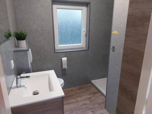 ein Bad mit einem Waschbecken, einem WC und einem Fenster in der Unterkunft Heerlijk vakantiehuis voor het gezin op de Veluwe in Epe