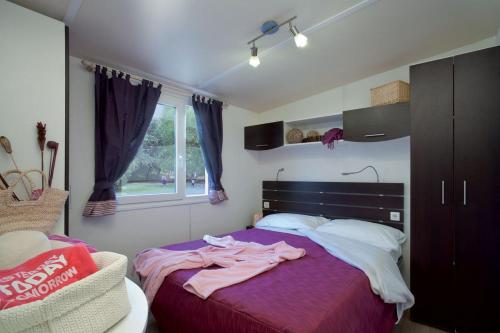 Un dormitorio con una cama con sábanas moradas y una ventana en Camping Badiaccia Village, en Castiglione del Lago