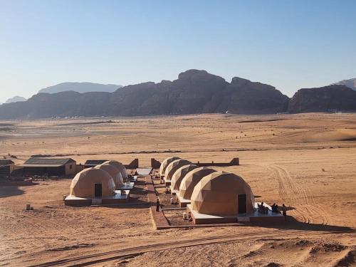 a row of tents in a desert with mountains in the background at Wadi Rum Ali Bubble camp in Wadi Rum