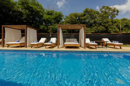 a swimming pool with chairs and a gazebo at Boutique Surf Hotel Rip Jack Inn in Playa Grande