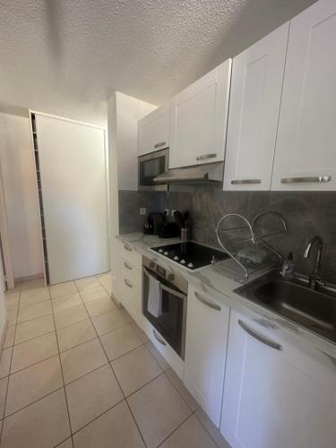 une cuisine avec des armoires blanches et un évier dans l'établissement Monaco Border, Terrace, Sea view & Parking, à Beausoleil
