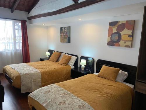een slaapkamer met 2 bedden en een raam en 2 lampen bij Quinta Hotel Las Buganvillas in Ambato