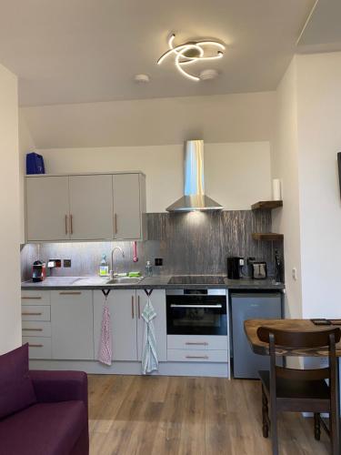 a kitchen with white cabinets and a stove top oven at Butterfly Cottage in Grantown on Spey