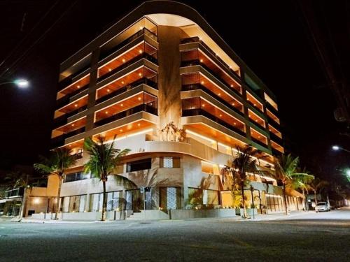 ein großes Gebäude mit Palmen davor in der Unterkunft Apartamento Alto padrão na praia do forte in Cabo Frio