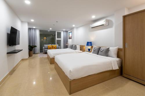 a hotel room with two beds and a flat screen tv at Shogun Hotel in Ho Chi Minh City