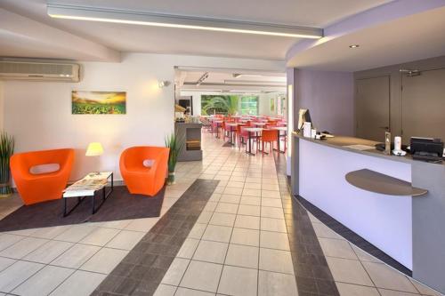 a restaurant with orange chairs and a dining room at Hôtel Formules Club in Cenon