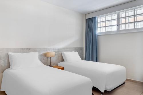 2 camas blancas en una habitación con ventana en Santa Barbara Golf and Ocean Club, en San Miguel de Abona