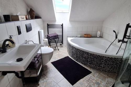 ein Badezimmer mit einer großen Badewanne und einem WC in der Unterkunft Ferienwohnung Casa Alotto in Windeck