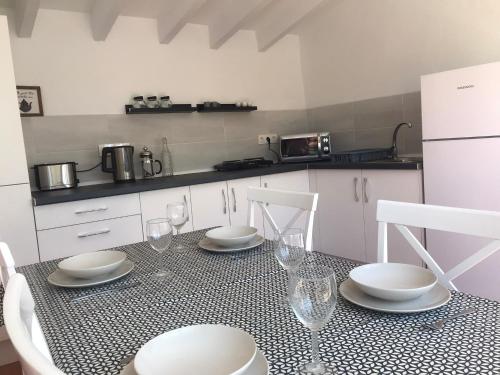uma cozinha com uma mesa com pratos e copos de vinho em Casa Tomas em Albox