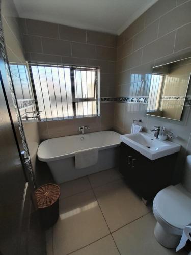 a bathroom with a tub and a sink and a toilet at The Executive 5 Bedroom in Manzini