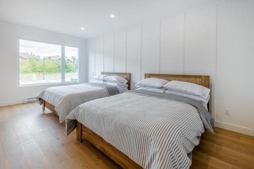 2 Betten in einem weißen Zimmer mit Fenster in der Unterkunft SOFA VILLAS MONT SAINTE-ANNE in Beaupré