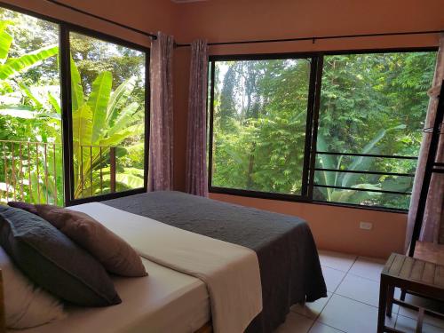 a bedroom with a bed and two large windows at Casa Palmera Cocles, 300m to the beach in Puerto Viejo
