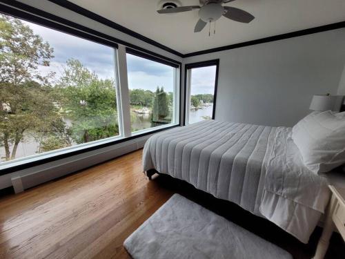1 dormitorio con 1 cama y ventanas grandes en Serene 5 Bedroom Waterfront Retreat Near BWI en Glen Burnie