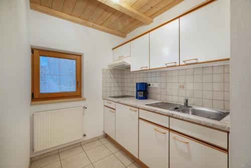 a kitchen with white cabinets and a sink at Tendershof Reschen in Resia