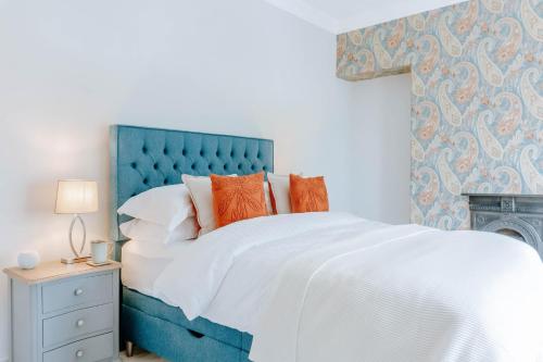 a bed with a blue headboard and orange pillows at The Harrogate Townhouse in Harrogate