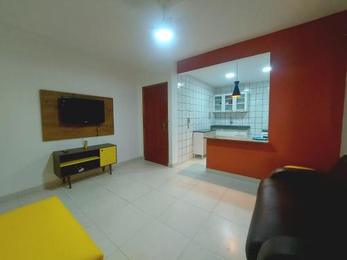 sala de estar con TV y cocina en Passar férias em Guarapari/praia do morro, apartamento aconchegante., en Guarapari