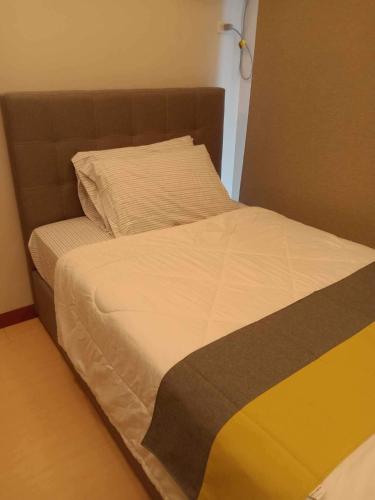 a bed with a brown headboard and white sheets at Homey 1Bedroom BGC Condo - MINIMUM 2 Nights stay in Manila