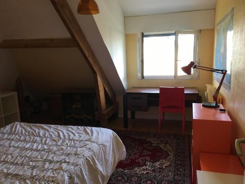 1 dormitorio con cama, escritorio y ventana en Chambre spacieuse et lumineuse en Mondeville