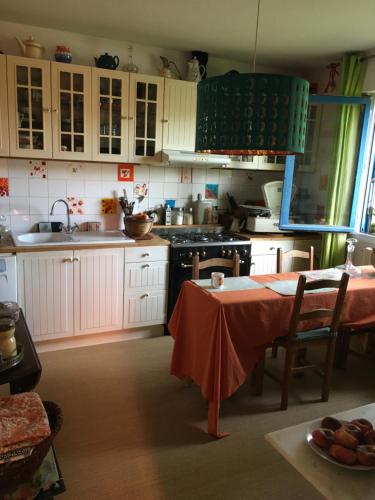 een keuken met witte kasten en een tafel. bij Chambre spacieuse et lumineuse in Mondeville