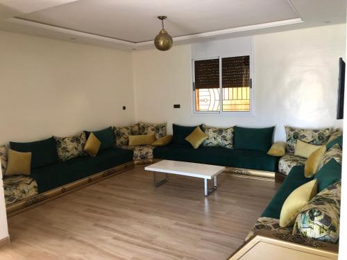 uma sala de estar com sofás verdes e uma mesa em Escape to Luxury Moroccan Villa with Pool Garden and Endless Sunshine Book Your Blissful Getaway Now em Sidi Bibi