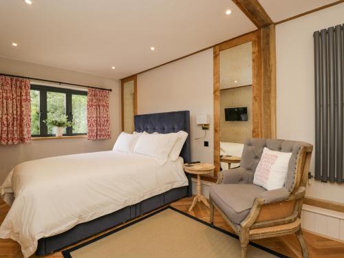 a bedroom with a bed and a chair at Cuckoo Penn Hideaway in Stonehouse