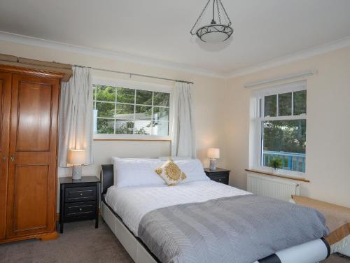 a bedroom with a bed and two windows at Tyddyn Ap Ifan in Penmaen-mawr