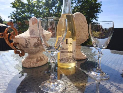 a bottle of wine and two glasses on a table at 2 Zimmer Domizil am Südhang mit Terrasse und Pool in Ortenberg