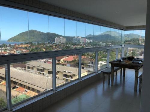 a room with a table and a view of a city at Vista Mar no Centro | Piscina | Vaga Garagem in Bertioga