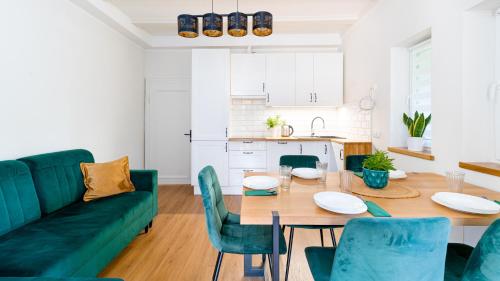 a living room with a green couch and a table and chairs at Apartament Lux pod Karpaczem in Miłków