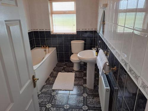 La salle de bains est pourvue d'une baignoire, de toilettes et d'un lavabo. dans l'établissement Buncronan Port Self Catering, à Donegal