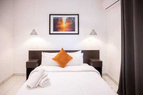 een slaapkamer met een groot wit bed en een oranje kussen bij Special 1 Bed Apt W/pool View @Embassy Gard 70m2 in Cantonments