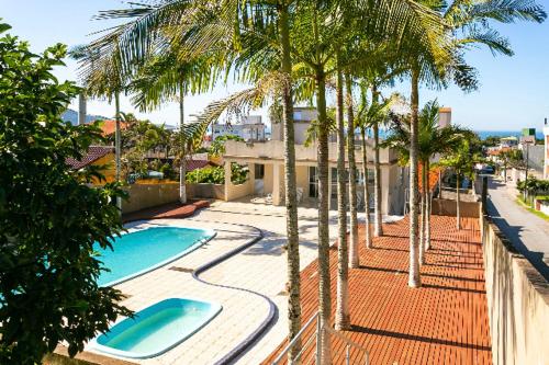 uma piscina com palmeiras junto a um edifício em Apartamento Santinho em Florianópolis