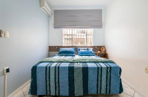 um quarto com uma cama num quarto com uma janela em Apartamento Santinho em Florianópolis